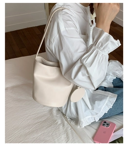 Detailansicht einer beige minimalistischen Beuteltasche mit passendem runden Münzetui