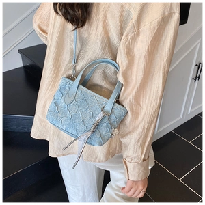 Detail of light blue bucket bag with star pleated texture and silver metallic charm