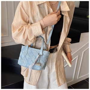 Detail of light blue pleated handbag with silver buckle and decorative lace tassel charm
