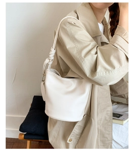 Detail einer weißen PU-Leder-Eimertasche mit stylischem Knotenschultergurt getragen am Model