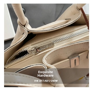 Detail of silver metal zipper with engraved logo on a beige textured leather handbag