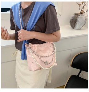 Détail du sac seau rose matelassé avec bandoulière en perles, breloque étoile et chaîne