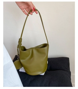 Detail der olivgrünen Eimer-Tasche aus Leder mit Schultergurt und passender kleiner Münzbörse
