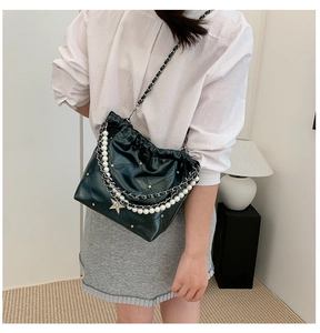 Détail du sac seau vert foncé avec chaîne de perles, breloques étoiles et rivets