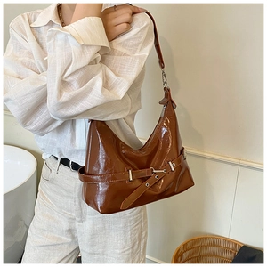 Close-up of brown glossy leather shoulder bag with side buckle and silver zipper