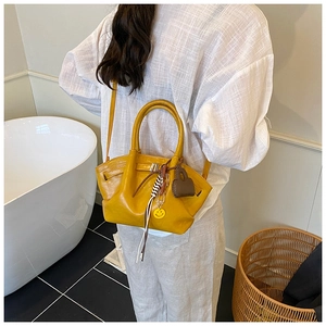 Detail of yellow pleated handbag with decorative buckle and strap shown in interior setting