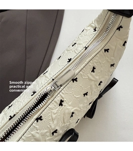 Detail of white quilted handbag with black butterfly embroidery and smooth silver zipper