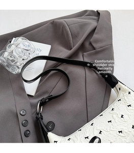 Detail of white pleated leather texture and black strap on a stylish shoulder bag