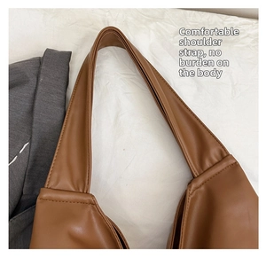 Detail shot of the wide brown leather shoulder strap with premium stitching on tote bag