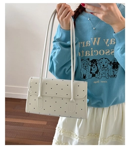 Detailed view of white shoulder bag with black heart prints and thin double straps