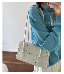 Close-up of white flap shoulder bag with black heart patterns and slim PU straps