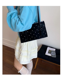 Detailed view of a black heart-patterned shoulder bag styled with a casual outfit
