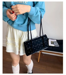 Detailed view of black shoulder bag with white heart patterns and double leather straps