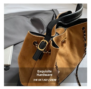Détail du sac seau en daim marron avec matelassage en losanges et chaîne dorée