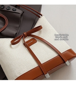 Close-up of canvas bucket bag with brown leather trim and decorative bow detail