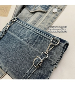 Detail of high-gloss silver hardware and rugged blue washed denim texture on crossbody bag