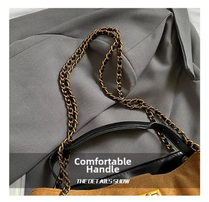 Détail du sac seau en daim marron avec poignée en cuir et bandoulière chaîne dorée