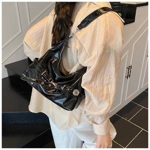 Detail of glossy black patent leather shoulder bag with silver buckle and metallic hardware