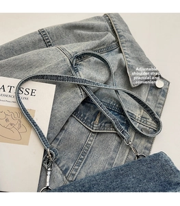 Detail of light blue denim crossbody bag with adjustable strap and silver metal hardware