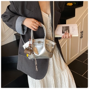 Detailed view of silver metallic handbag with smooth finish and mini charm accessory