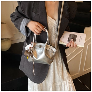 Detail of silver metallic tote bag with brown charm accessory on a casual suit