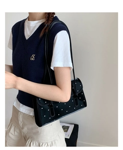 Detail of black underarm bag featuring white heart print and dual leather straps