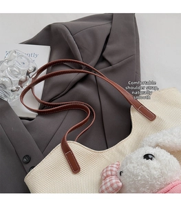 Dettaglio tracolla in pelle marrone su borsa tote in tessuto beige con ciondolo a coniglio