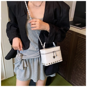 Mini borsa a scatola trapuntata con ciondolo a cuore indossata a tracolla da modella