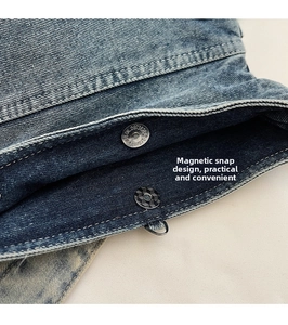 Detail of the magnetic buckle closure on a durable blue denim crossbody shoulder bag