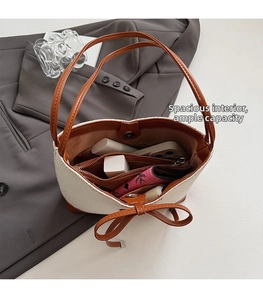 Spacious interior of canvas bucket bag with brown leather bow and zip pocket