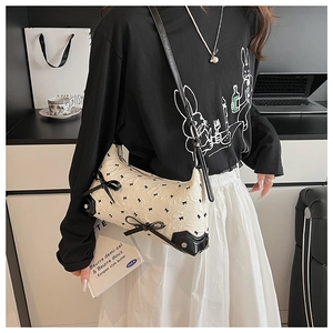 Detail of cream jacquard shoulder bag featuring black bows and contrasting leather piping
