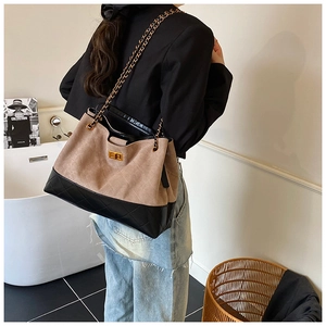 Détail d'un grand sac cabas bicolore avec bandoulière chaîne et fermoir pivotant doré sur modèle