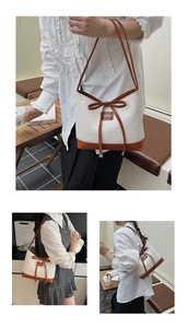 Detail view of woven straw shoulder bag with brown leather trim and bow decoration