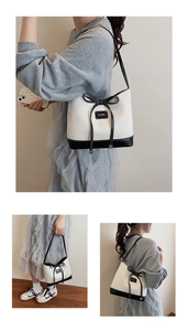 Detail of contrast straw bucket bag with black leather bow and refined stitching texture