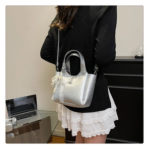 Silver metallic bucket bag detail with elegant pearl string and white lace bow accessory