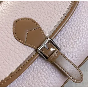 Macro detail of pink lychee grain leather and brown strap with silver metal buckle