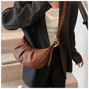 Sac à bandoulière demi-lune plissé marron en cuir grainé porté par un mannequin