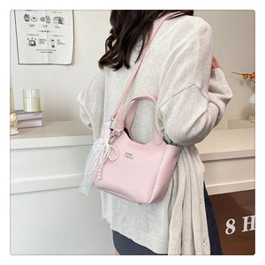 Detail view of pink lychee leather bucket bag with pearl lace charm and logo