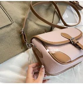 Close-up of pink and brown leather crossbody bag featuring pebble texture and contrast stitching
