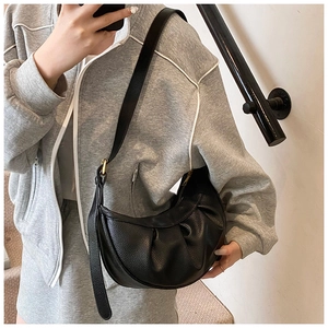 Détail du sac croissant en cuir grainé noir montrant la texture et la bandoulière réglable