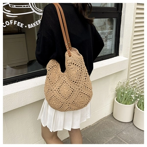 Detail of hand-crocheted hollow straw bag with brown leather straps and geometric texture