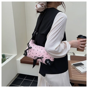 Macro view of pink pleated handbag with black bow embroidery and leather details