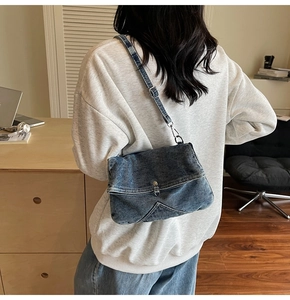 Close-up of a vintage denim crossbody bag showing adjustable metal buckle and stitching