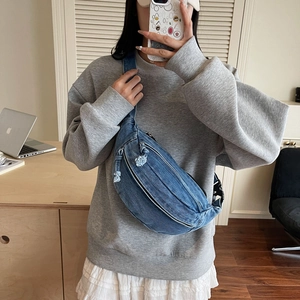 Mirror selfie showing the scale of a blue denim crossbody bag with frayed edges