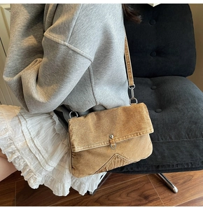 Détail d'un sac messager rétro en denim kaki avec boucle métallique sur fond sombre