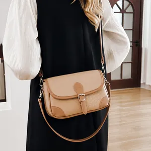 Close-up of khaki lychee grain leather crossbody bag with vintage buckle and silver hooks