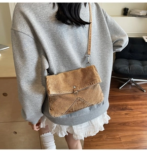Rear view of model wearing a vintage brown denim crossbody bag in a cozy home interior