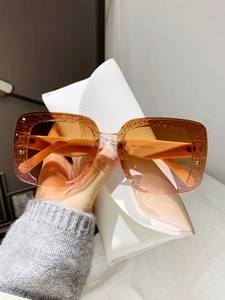 Détail de lunettes de soleil carrées demi-cerclées à paillettes avec étui en cuir blanc