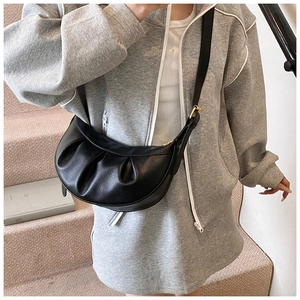 Détail du sac demi-lune en cuir grainé noir avec plis et boucle métallique dorée