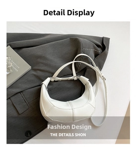 Close-up of white crescent shoulder bag in lychee texture leather on a grey suit